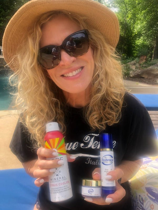 Woman holding Vitali Restorative Serum and sunscreen products.